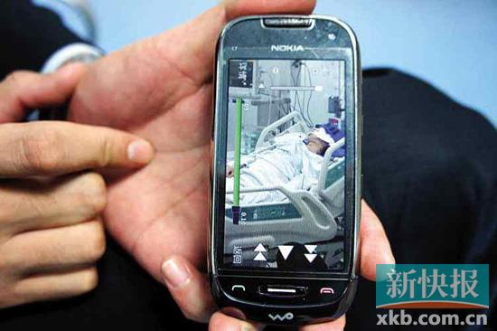 丁喜桥的同事用手机向记者展示丁喜桥在ICU病房里的情况。