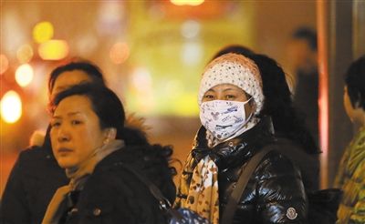 一位市民戴着口罩在国贸等公交车。