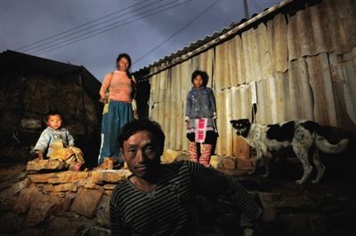 云南省开远市红坡头村，吴笑林一家在自己的棚屋前。他们一家和村里大多数人一样都没有户口，不能外出务工，只能靠种地过活，全家年收入5千元左右。当地每户人家都有好几个孩子，住简陋的棚屋，生活水平非常低。