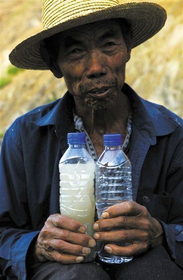 3月21日，一位村民拿着两瓶水，里面是小江水和普通矿泉水的对比