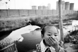 排污沟旁边，一个小女孩被熏得捂住鼻子