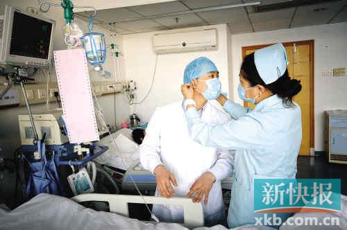 一位女护士正帮一名男护士戴好帽子，在照顾病人方面他们具备同样的耐心和细致