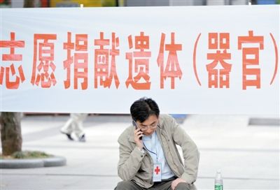 2013年5月7日，南京，一名红十字会工作人员在志愿捐献遗体（器官）的横幅前打电话