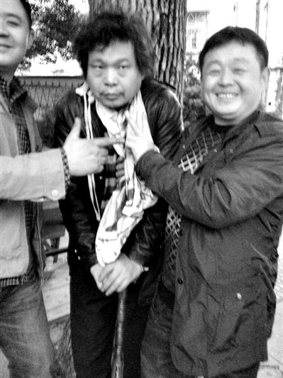 两名接访人员与患有癌症的访民段新德合影时，面带笑容摆出胜利的手势