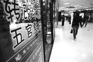 江东彩虹服饰广场，一位市民从一家文绣美容会所前走过